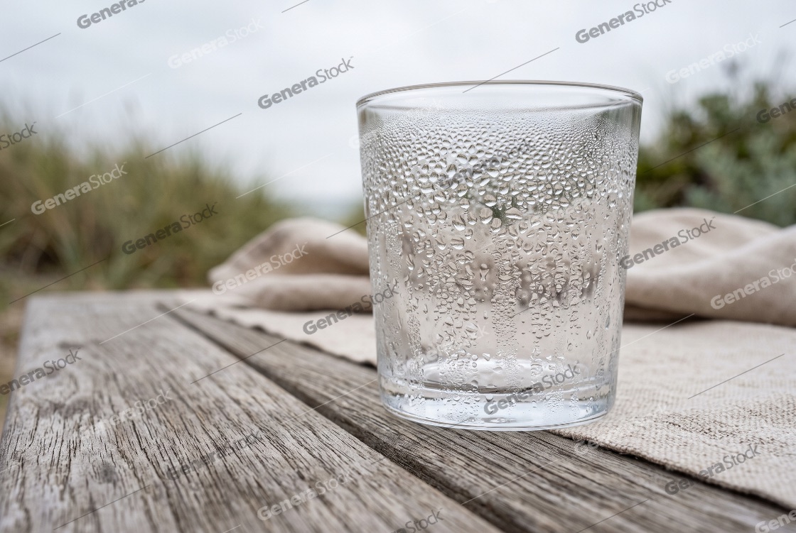 An empty cold drinking glass covered with condensation water dro