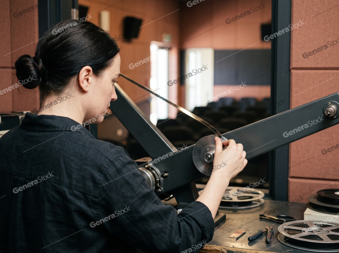 A young female archivist and projectionist carefully mounting a