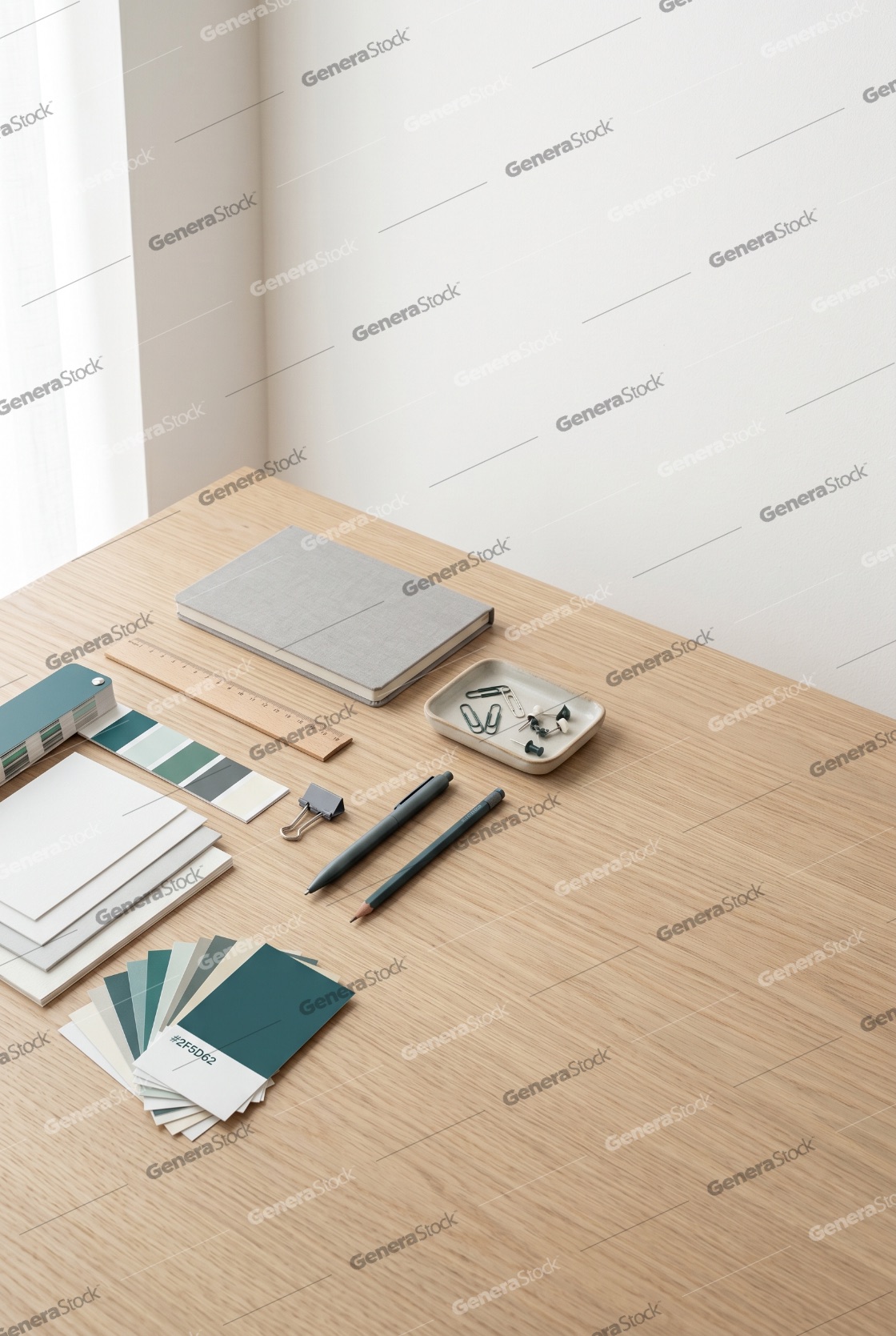 Minimalist creative workspace with color swatches, notebook, and stationery on a wooden desk
