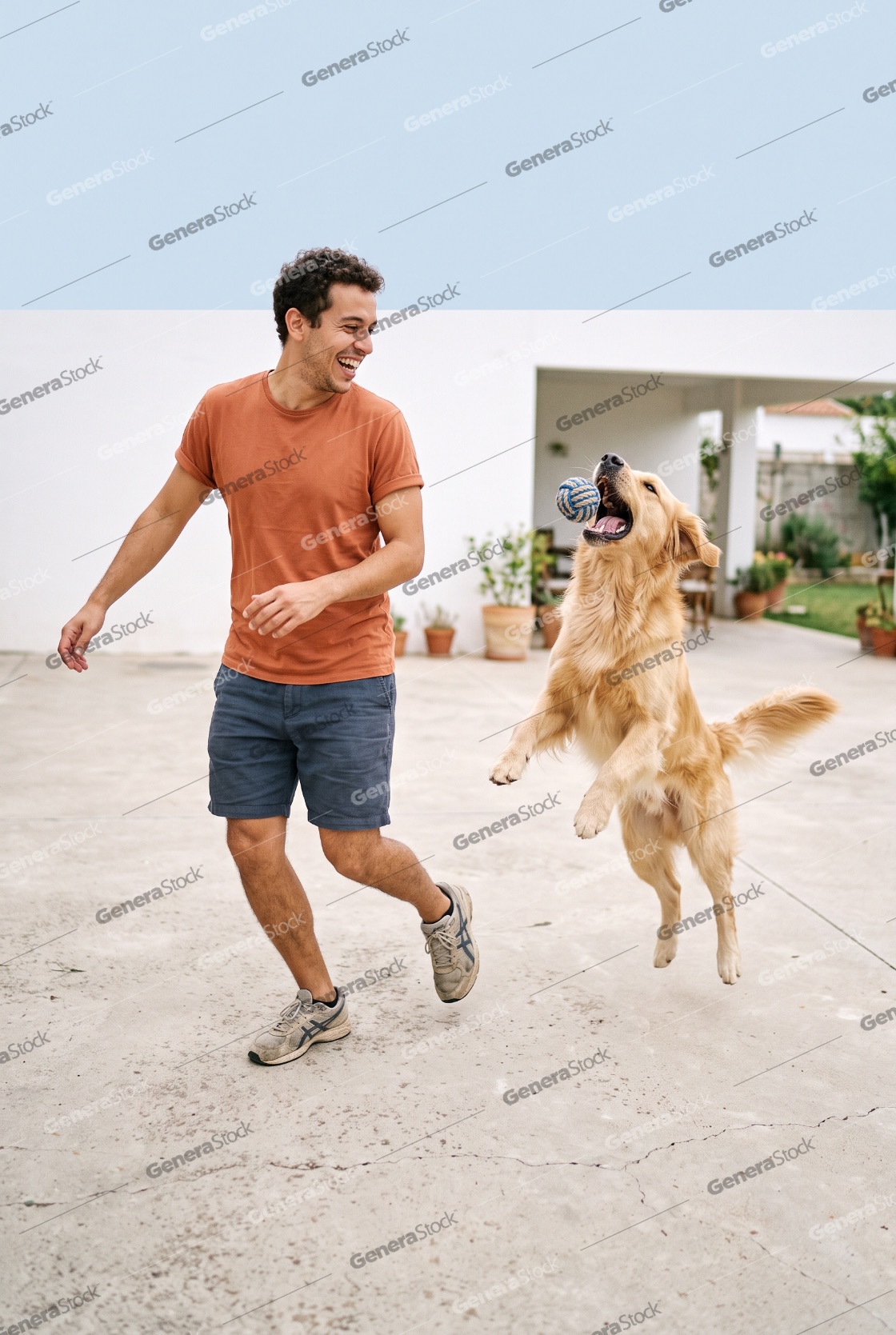 A happy young man playing fetch with his excited golden retrieve