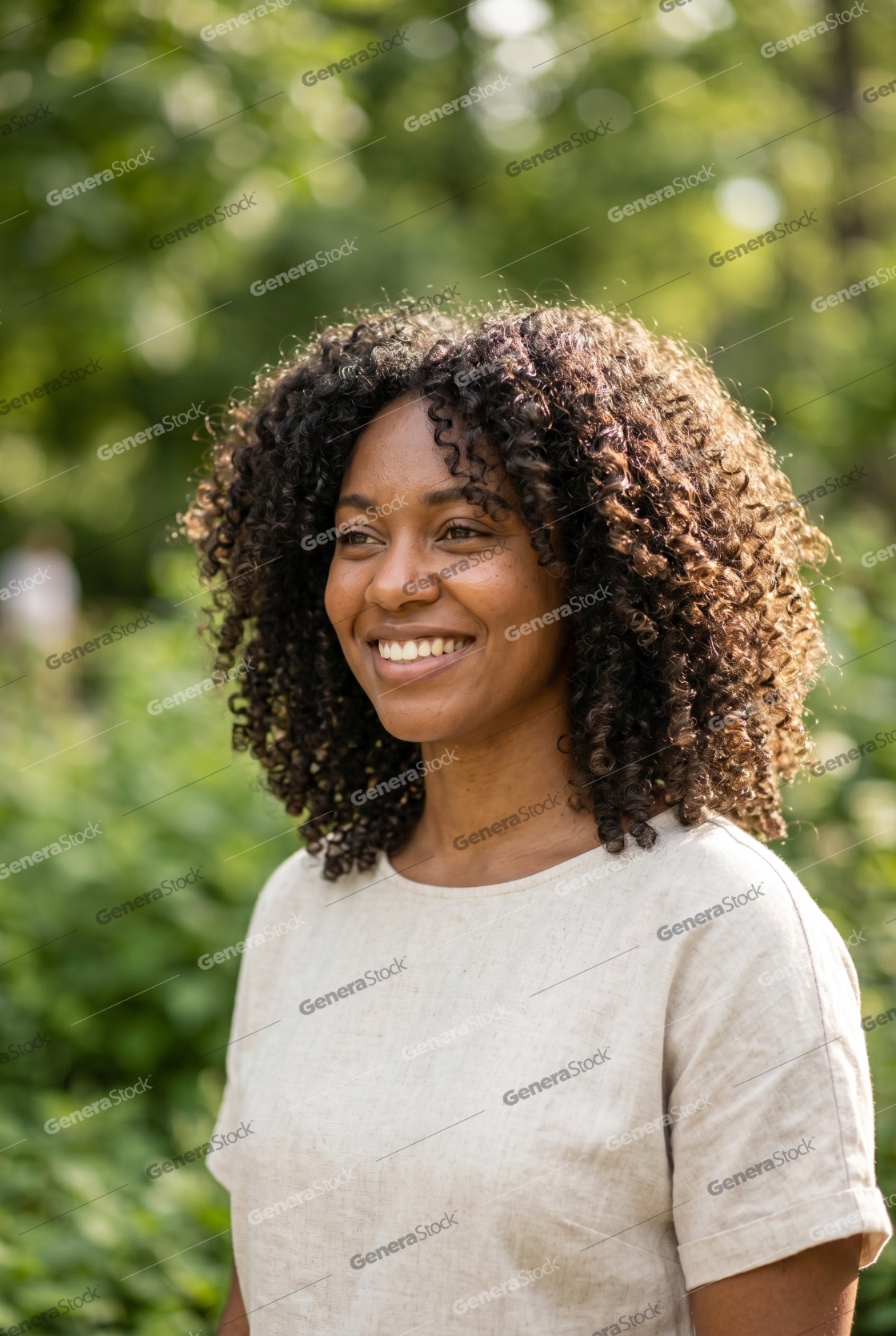 Portrait of a beautiful young Black woman with natural curly hair smiling in a sunlit park