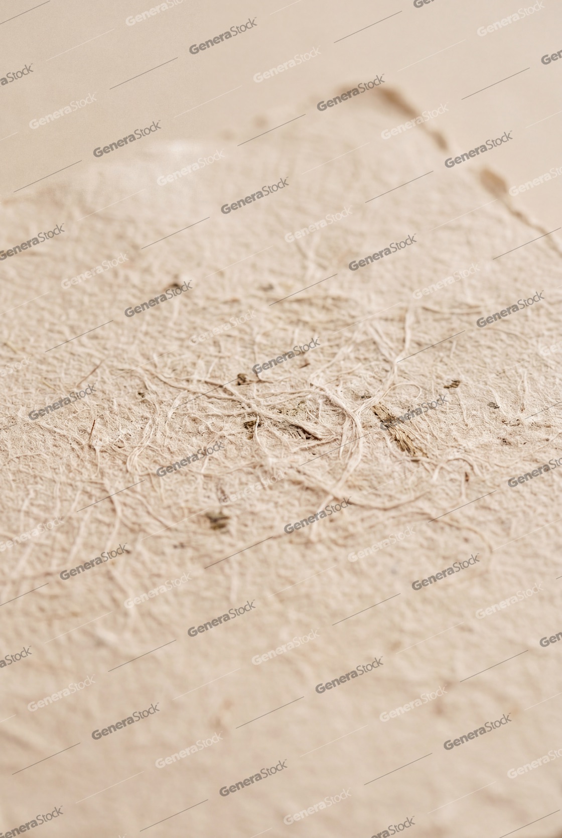 Macro shot of beige artisanal handmade paper showing organic fibrous texture and deckle edge