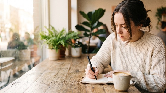 young, woman, focused, writing, notebook, cozy, cafe, table, with, coffee, journal, studying, student, freelancer, lifestyle, sweater, working, planning, creative, thinking, indoor, wooden, latte, morning, peaceful, focus, education, hobby, person, adult, casual, plants, window, natural, light, leisure, productivity, diary, pen, notes, inspiration, solitude, relaxation, shop, business, remote, work, writer, blogger, people