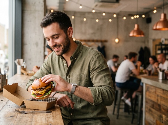 smiling, young, man, enjoying, large, gourmet, cheeseburger, wooden, table, trendy, urban, restaurant, burger, eating, food, lifestyle, lunch, cafe, casual, meal, happy, adult, male, delicious, fast, dining, industrial, interior, hungry, tasty, takeout, dinner, people, person, beard