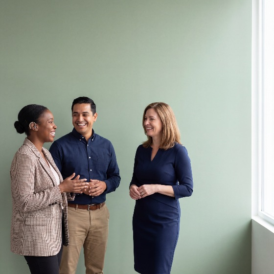 diverse, group, three, business, professionals, including, woman, with, hearing, aid, laughing, and, talking, together, bright, office, space, green, wall, natural, window, light, professional, diversity, inclusion, disability, colleagues, coworkers, team, meeting, conversation, happy, success, communication, workplace, accessibility, people, corporate, career, collaboration, partnership, adult, attire, casual, modern, indoor, lifestyle, friendship, support, empowerment, equality, multi-ethnic, multicultural, teamwork, positive, smiling, interaction, representative, loss, assistive, technology, cochlear, implant, finance