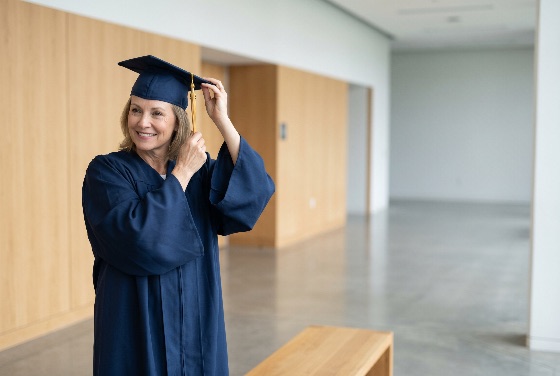 smiling, mature, woman, graduate, blue, cap, and, gown, adjusting, her, tassel, graduation, day, senior, student, education, achievement, success, mortarboard, happy, proud, lifelong, learning, adult, university, college, ceremony, academic, celebration, indoor, hallway, modern, lifestyle, female, middle-aged, career, goal, future, diploma, degree