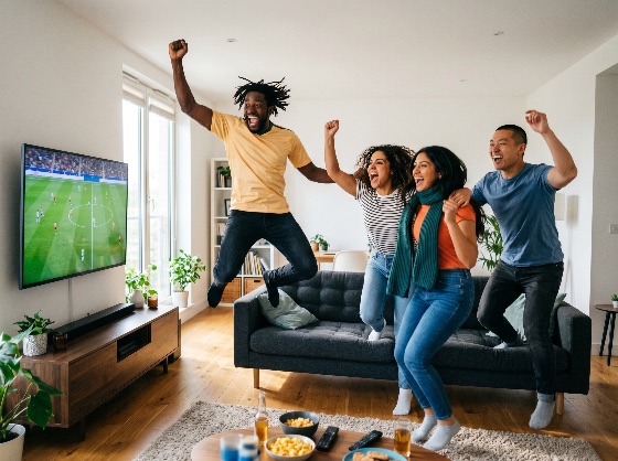 diverse, group, excited, friends, jumping, and, cheering, while, watching, soccer, match, television, modern, living, room, football, celebrating, goal, victory, excitement, home, multicultural, fans, sports, game, joy, happiness, together, lifestyle, leisure, interior, apartment, snacks, drinks, beer, chips, shouting, screaming, winning, team, support, friendship, young, adults, men, women, indoor, day, bright, people