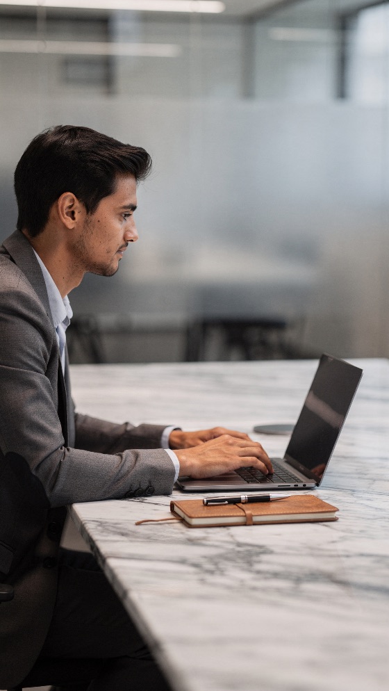 professional, young, businessman, grey, suit, working, lapto, side, profile, typing, laptop, marble, desk, leather, notebook, and, pen, sit, nearby, bright, modern, office, workspace, business, man, corporate, technology, computer, entrepreneur, focused, executive, career, success, adult, male, view, indoor, productivity, management, finance, consultant, freelancer, digital, internet, communication, formal, attire, workplace, job, occupation, startup, concentration, people, lifestyle, stationery, elegant