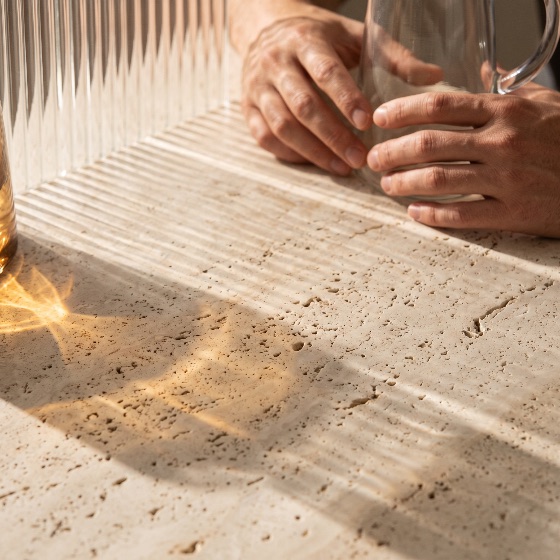 close, person, hands, holding, clear, glass, pitcher, high-angle, close-up, scene, featuring, resting, near, textured, beige, travertine, stone, tabletop, warm, natural, sunlight, filters, through, ribbed, casting, linear, light, and, shadow, patterns, across, the, surface, along, with, golden, optical, reflections, ideal, for, modern, aesthetic, lifestyle, interior, design, concepts, jug, reeded, fluted, refraction, pattern, texture, minimalist, counter, marble, caustics, glare, hour, morning, concept, drinkware, transparent, touch, tactile, luxury, elegance, play, background, architectural, abstract, reflection, sunbeam, warmth, detail, backgrounds, textures