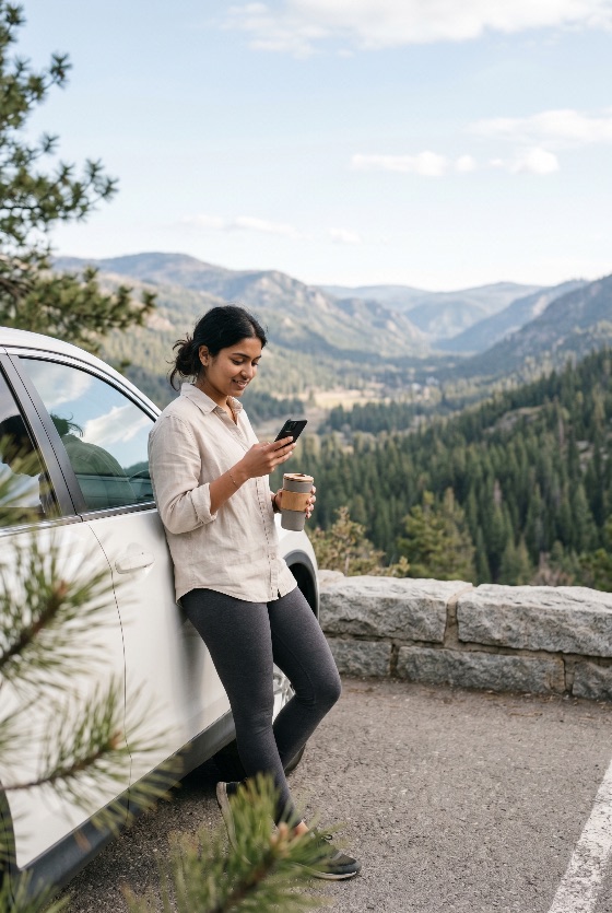 young, woman, road, trip, leaning, against, her, car, and, using, smartphone, mountain, overlook, travel, nature, scenery, view, coffee, reusable, cup, mobile, phone, technology, vacation, adventure, lifestyle, smiling, happy, outdoors, forest, valley, landscape, tourism, leisure, solo, traveler, connectivity, communication, digital, nomad, driving, stop, break, scenic, summer, spring, daytime, casual, leggings, shirt, white, suv, parking, stone, wall, mountains, trees, pine, evergreen, wilderness, landscapes