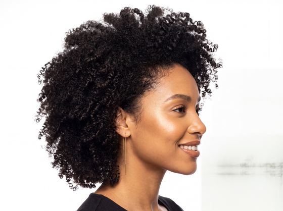 woman with natural curls in profile, clean white background, studio light